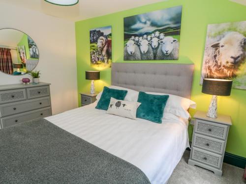 a bedroom with a bed with green walls at Herdwick Cottage in Brampton