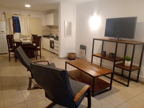 ein Wohnzimmer mit einem TV, einem Tisch und Stühlen in der Unterkunft Departamentos Uma in San Rafael