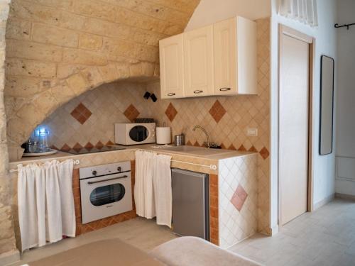 a kitchen with white appliances and a stone wall at CASA BEATA ELIA in Bari