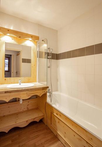 une salle de bain avec un lavabo, une baignoire et un miroir dans l'établissement Hameau 6 002 - SPA & PISCINE studio 4 pers, à Orelle