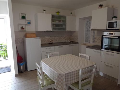 a kitchen with a table and a kitchen with white cabinets at Apartment Perica - 10 m from sea in Postira