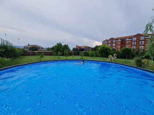 uma grande piscina azul com edifícios ao fundo em Green Villa Rodna em Skopje