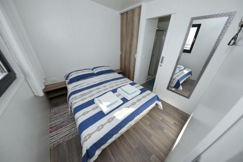 a bedroom with a bed with a blue and white blanket at Mobile home Safir in Biograd na Moru