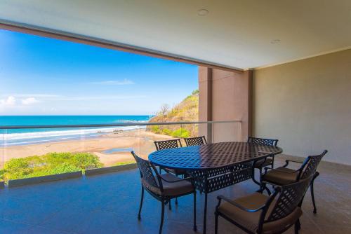 a table and chairs on a balcony with a view of the beach at Break Water Point Penthouse 7th Floor in Jacó
