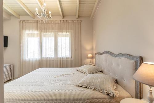 a white bedroom with a large bed with a chandelier at Black Velvet in Agkidia