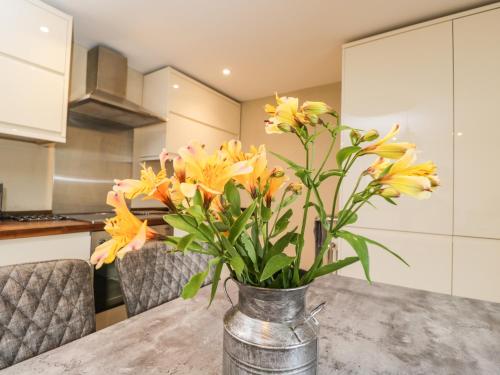 a vase with yellow flowers on a table in a kitchen at The Coach House in Tetbury