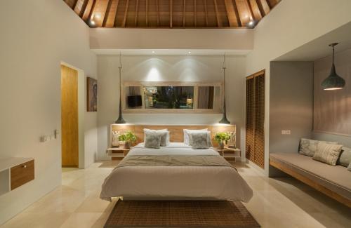 a bedroom with a large bed and a couch at Villa Sanook in Seminyak