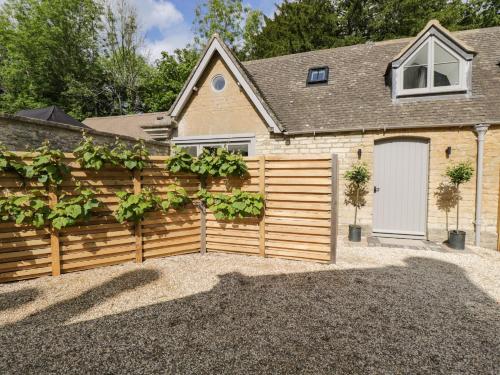 a house with a wooden fence and a garage at The Hayloft in Tetbury