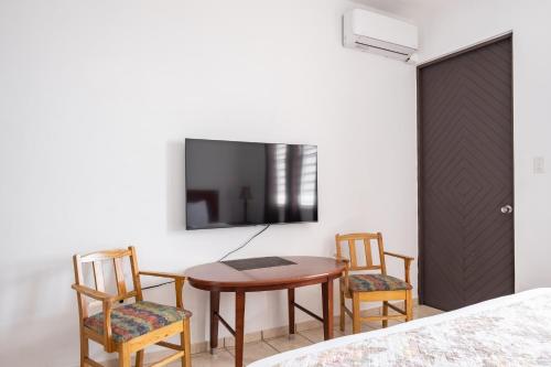 a room with a table and chairs and a tv at Hacienda Margarita in Barranquitas