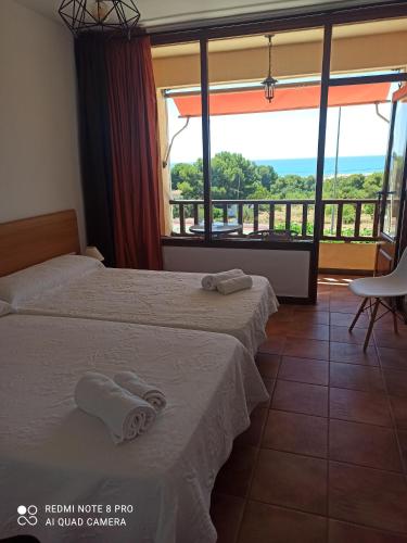 a hotel room with two beds and a balcony at Hotel Serra D'írta in Alcossebre