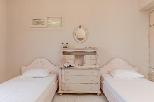 two beds in a room with a dresser and a mirror at Black Velvet in Agkidia