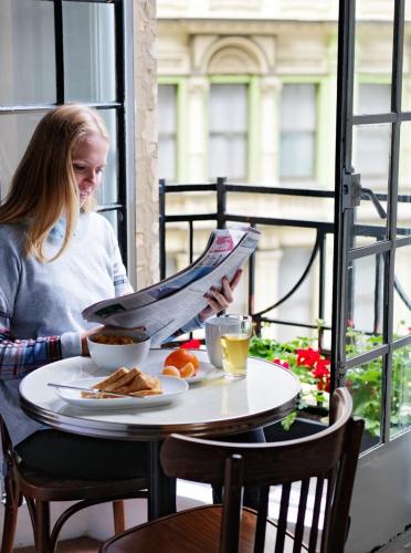 a young girl sitting at a table with a newspaper at Grand Hotel Sydney in Sydney