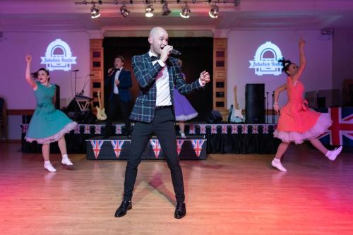 a man singing into a microphone on a dance floor with two dancers at TLH Toorak Hotel - TLH Leisure, Entertainment and Spa Resort in Torquay