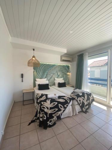 a bedroom with two beds and a large window at Hôtel Les Sables - Urban Style - by Logis Hotels in Canet-en-Roussillon