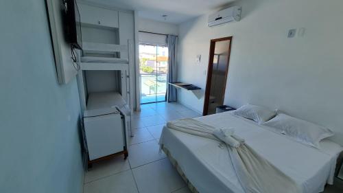 1 dormitorio con cama blanca y balcón en Xodó do Peró Hostel, en Cabo Frío