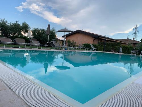 a large swimming pool with blue water at Agriturismo La Palazzina in Castelnuovo del Garda