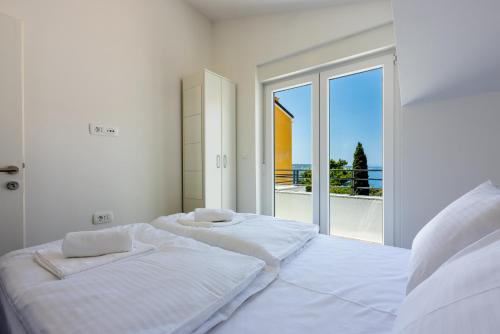 two beds in a white room with a large window at Luxury Apartments Lovorka 3 & 4***/**** in Selce