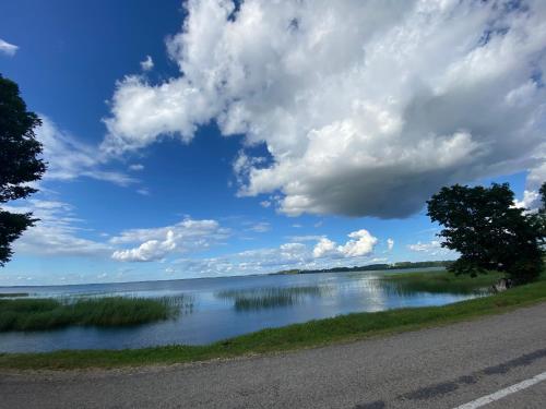 a road next to a lake under a cloudy sky at AVapartment in Lipuški