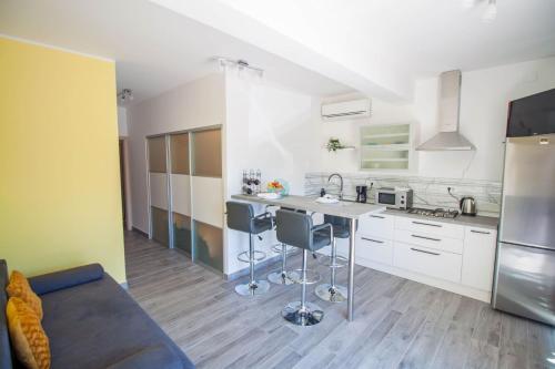 uma cozinha com armários brancos e uma ilha de cozinha com bancos de bar em Apartment Smile em Opatija