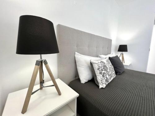 a black lamp sitting on a table next to a bed at Nancy Apartment - Near Vilamoura Marina by HD PROP in Vilamoura