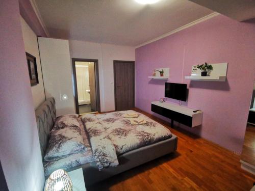 a bedroom with a bed and a purple wall at Exclusive Skopje Apartments in Skopje