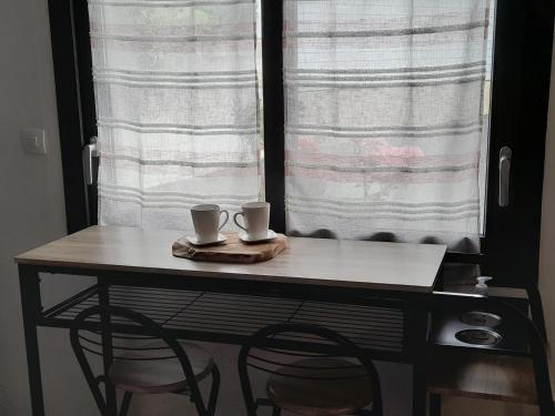 una mesa con dos tazas encima frente a una ventana en Les Fines Bulles & spa, en Bourseville