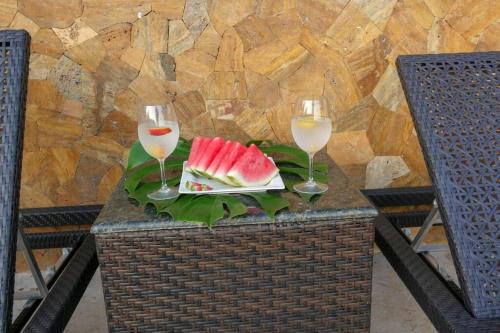 a table with two glasses of wine and a plate of watermelon at Casa Sol in Herradura