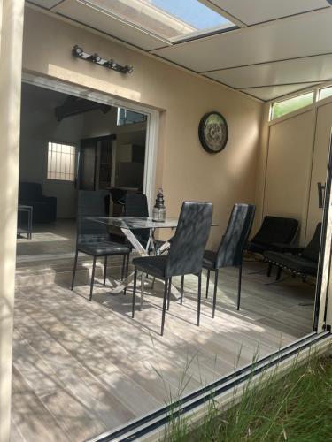 a patio with chairs and a table and a clock at Olympic Games 20 min from Paris and CDG Aeroport Luxurious House with garden and parking in Eaubonne