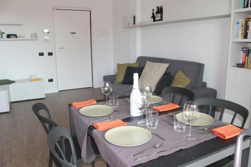 a table with plates and wine glasses and a couch at Borgo Apartments Borgo 56 in Borgomanero