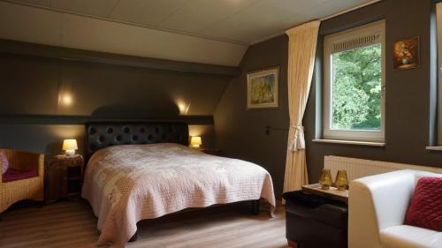 a bedroom with a bed and a window and a couch at B&B aan het bos in Ter Apel