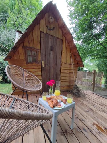 une table avec de la nourriture sur une terrasse avec une cabane dans l'établissement Cabane Insolite Magique & Spa Privatif Camping Canal de Nantes à Brest, à Guenrouet