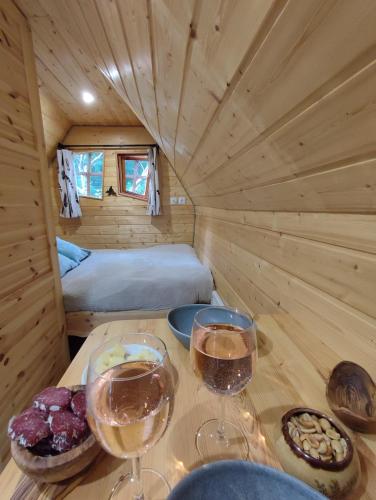 - une table avec deux verres de vin et un lit dans l'établissement Cabane Insolite Magique & Spa Privatif Camping Canal de Nantes à Brest, à Guenrouet