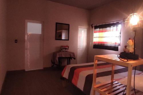 a bedroom with a bed and a table and a window at Casa de huéspedes con lo que necesitas para ti in San Pablo Villa de Mitla
