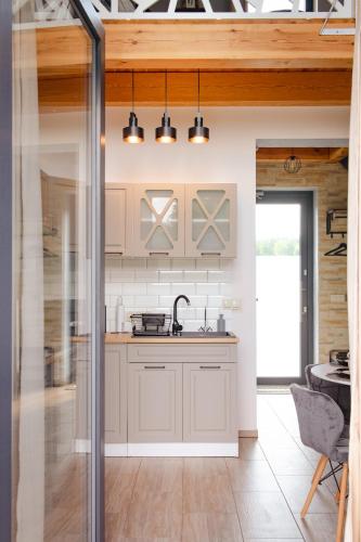 an open kitchen with white cabinets and a table at Osada Za Dębami, Podlasie, Sejny in Sejny