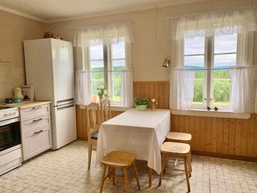 a kitchen with a table and two chairs and two windows at Landlig leilighet in Landsem