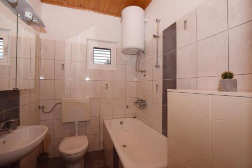 a white bathroom with a toilet and a sink at Apartments Andrija in Pirovac