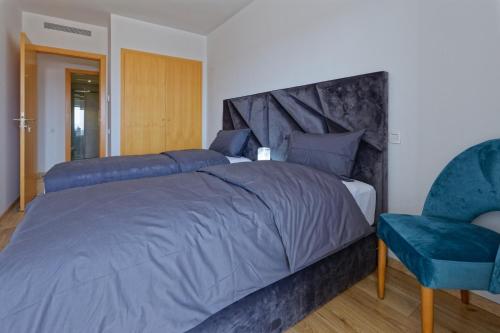 um quarto com uma cama grande e uma cadeira azul em Luxury Apartment 100sqm with Pool near Beach WIFI Unlimited with Optical Fiber em Agadir