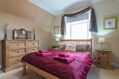 a bedroom with a large bed with pink towels on it at The Old School House - Cosy 3 bedroom Cottage in Wick