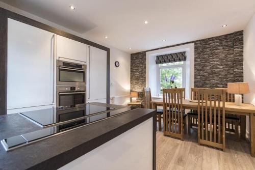 a kitchen and dining room with a table and a counter top at The Old School House - Cosy 3 bedroom Cottage in Wick