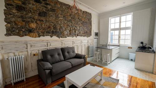sala de estar con sofá y pared de piedra en APARTAMENTOS RAMAR 1, en Pravia