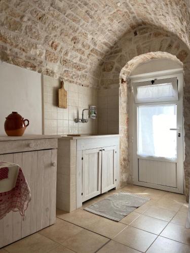 a kitchen with a sink and a door with a window at Trullo Zia Nina in Alberobello