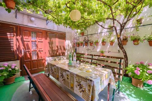 a table and a bench in a room with plants at Apartman Ana in Mali Lošinj