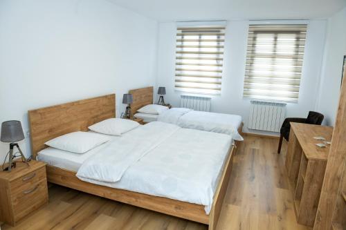 a bedroom with two beds and a desk and two windows at Guest House Alte in Kolašin