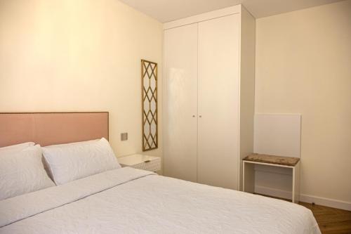 a white bedroom with a bed and a table at Apartamentos La Quinta in Burgos