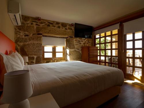 a bedroom with a large bed and a stone wall at Casa da Mãe - Izei in Chaves