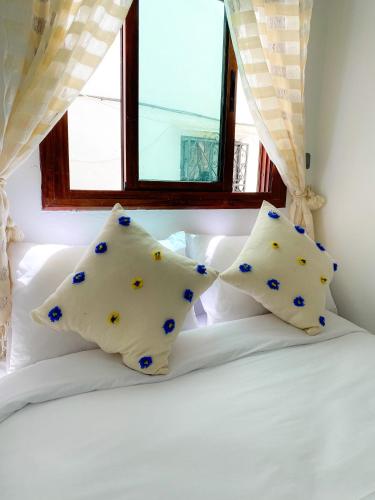 a bed with two pillows on it with a window at DAR ADIL KASBAH in Tangier