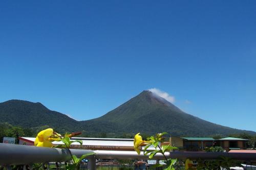 a mountain in the distance with a building and a fence at Hotel Las Colinas in Fortuna