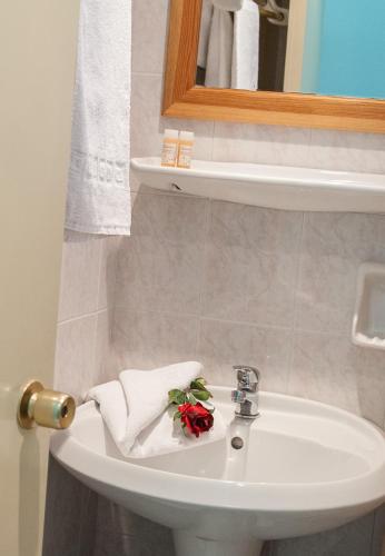 a bathroom with a sink with towels and a flower on it at Bozikis Palace Hotel in Laganas