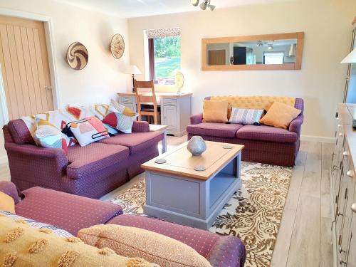 a living room with two couches and a table at Upper Rosemount Lodge in Blairgowrie