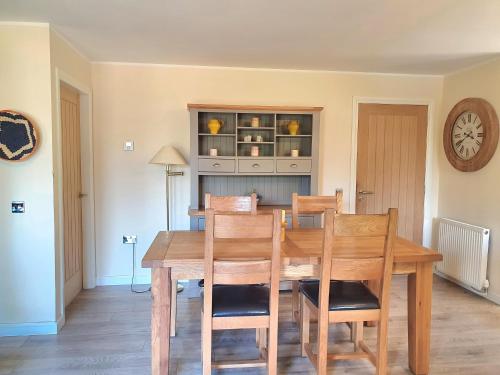 a dining room with a wooden table and chairs at Upper Rosemount Lodge in Blairgowrie